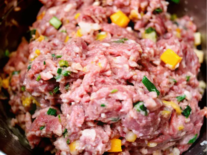 How to Make Delicious Jalapeno Cheddar Sausage: The Ultimate Recipe 5 A close-up image of a bowl filled with a mixture of ground meat, diced jalapeños, and shredded cheddar cheese.