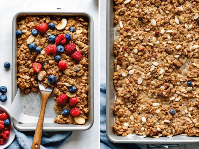 A baking sheet filled with homemade granola, topped with fresh strawberries and blueberries.